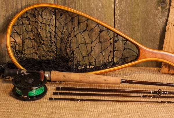 Fly fishing gear on burlap against ceader wood wall — Stock Photo, Image