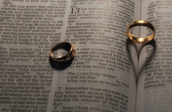 Snubní prsteny, takže srdce tvaru stíny na stránky bible — Stock fotografie
