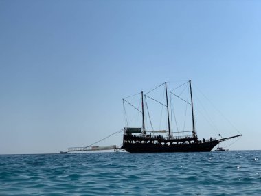 Açık denizlerde yelkenli. Yat deniz kıyısında yelken açar. Mavi gökyüzüne karşı küçük bir gemi