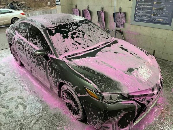 Araba yıkamada köpüklü araba, yıkama sırasında Tayota Camry. Konsept: yıkanmış yolcu vagonu. Kiev bölgesi, Irpin şehri, 3 Aralık 2021