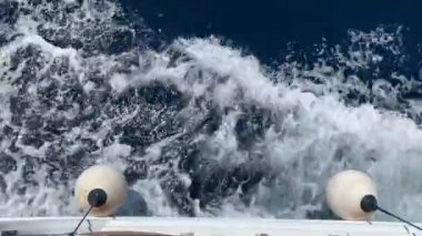 Deniz gemisinin yan tarafındaki su akıntısı. Bir yelkenli gemisinden deniz sıçramaları. Yelkenli yatın yüksekliğinden su manzarası.