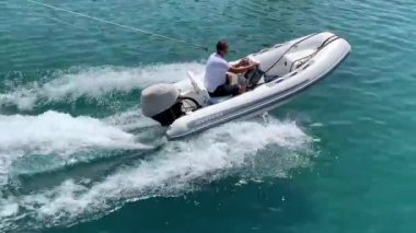 Motorlu tekne denizde yelken açar. Denizdeki deniz gemisi tam hızda. Yat adanın yakınından geçiyor. Oludeniz 'den 12 ada turu - Fethiye, Türkiye, 10 Ağustos 2021.