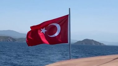 Bayrak denizin ve güneşin arka planında dalgalanıyor. Sembollü Türk deniz gemisi. Rüzgarda hilal şeklinde ay olan kırmızı Türk bayrağı.