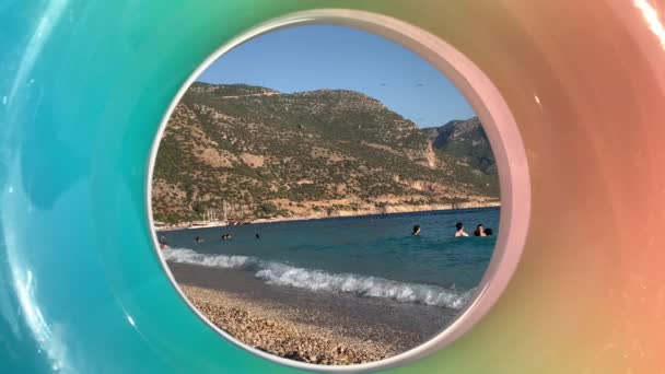海では 膨脹可能なリングを見下ろす水泳 山を背景にした夏の海の海岸 人々が休んで海岸 トルコOludeniz ブルーラグーン12 8月2021 — ストック動画