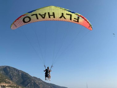 Türkiye 'de paraşütle atlama. Gökyüzünün arka planında paraşütle atlamak. Toz sporu, yamaç paraşütü. Türkiye, Babadag Dağı, Oludeniz, 8 Ağustos 2021