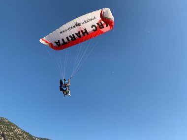 Türkiye 'de paraşütle atlama. Gökyüzünün arka planında paraşütle atlamak. Toz sporu, yamaç paraşütü. Türkiye, Babadag Dağı, Oludeniz, 8 Ağustos 2021