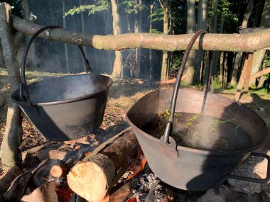 Kamp kazanındaki su ateşin üzerinde kaynıyor. Ateşin üzerinde büyük bir tencerede yemek pişirmek. Kavram: dağlarda yürüyüş, ormanda kamp, ateşte yemek..