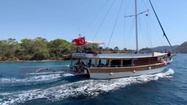 Deniz koyuna yakın lüks bir yat yelken açar. Orta karasal denizde özel bir tekne yüzüyor. Deniz kıyısına yakın denizde yelkenli bir tekne. Türkiye, Fethia, 12 ada turu, 9 Ağustos 2021.