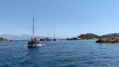 Deniz koyuna yakın lüks bir yat yelken açar. Orta karasal denizde özel bir tekne yüzüyor. Deniz kıyısına yakın denizde yelkenli bir tekne. Türkiye, Fethia, 12 ada turu, 9 Ağustos 2021.