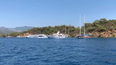 Deniz koyuna yakın lüks bir yat yelken açar. Orta karasal denizde özel bir tekne yüzüyor. Deniz kıyısına yakın denizde yelkenli bir tekne. Türkiye, Fethia, 12 ada turu, 9 Ağustos 2021.