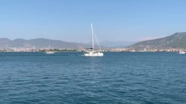 Deniz koyuna yakın lüks bir yat yelken açar. Orta karasal denizde özel bir tekne yüzüyor. Deniz kıyısına yakın denizde yelkenli bir tekne. Türkiye, Fethia, 12 ada turu, 9 Ağustos 2021.