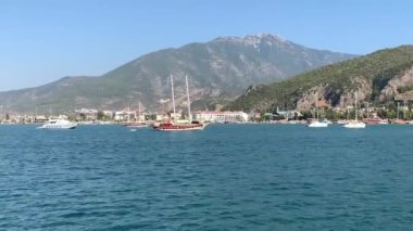 Deniz koyuna yakın lüks bir yat yelken açar. Orta karasal denizde özel bir tekne yüzüyor. Deniz kıyısına yakın denizde yelkenli bir tekne. Türkiye, Fethia, 12 ada turu, 9 Ağustos 2021.