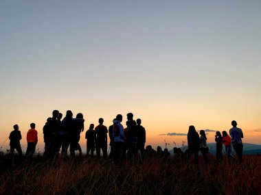 Günbatımının arka planında genç insanların siluetleri. Dağın tepesindeki gençler gün batımını izliyorlar. Karpatlar, Ukrayna 'daki gençlik kampı, 30 Temmuz 2021