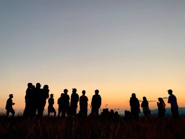 Günbatımının arka planında genç insanların siluetleri. Dağın tepesindeki gençler gün batımını izliyorlar. Karpatlar, Ukrayna 'daki gençlik kampı, 30 Temmuz 2021