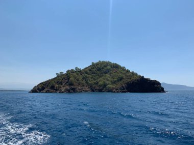 An uninhabited island in the Mediterranean. Seashore against the backdrop of mountains and clear sea. Islands surrounded by the sea, a quiet harbor for yachts.