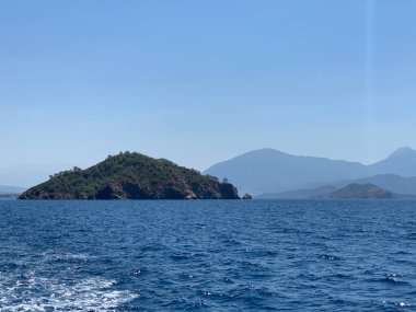 An uninhabited island in the Mediterranean. Seashore against the backdrop of mountains and clear sea. Islands surrounded by the sea, a quiet harbor for yachts.
