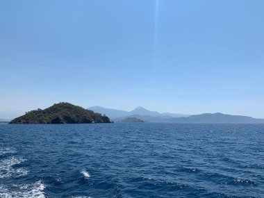 An uninhabited island in the Mediterranean. Seashore against the backdrop of mountains and clear sea. Islands surrounded by the sea, a quiet harbor for yachts.