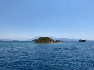 An uninhabited island in the Mediterranean. Seashore against the backdrop of mountains and clear sea. Islands surrounded by the sea, a quiet harbor for yachts.