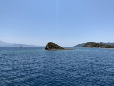 An uninhabited island in the Mediterranean. Seashore against the backdrop of mountains and clear sea. Islands surrounded by the sea, a quiet harbor for yachts.