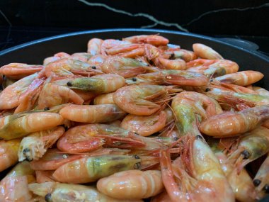 Soslu karides. Kızartma tavasında karides olan bir tabak. Baharatlı deniz ürünleri pişirmek, yakın plan..