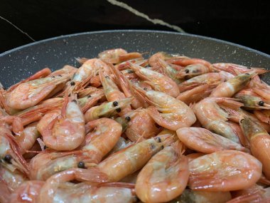 Soslu karides. Kızartma tavasında karides olan bir tabak. Baharatlı deniz ürünleri pişirmek, yakın plan..