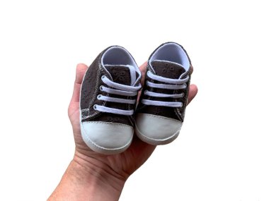 Eldeki bebekler için terlikler. En küçük çocuklar için ayakkabılar. Küçük bedenli, beyaz tenli çocuk ayakkabıları..