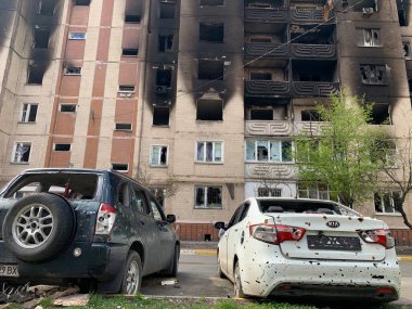 Yıkılan binaların arka planında yanmış ve bomboş bir araba. Evin kalıntıları ve arabanın gövdesinde kurşun izleri var. Rusya ve Ukrayna arasındaki savaş, Irpin-Bucha, 10 Nisan 2022