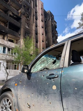 Yıkılan binaların arka planında yanmış ve bomboş bir araba. Evin kalıntıları ve arabanın gövdesinde kurşun izleri var. Rusya ve Ukrayna arasındaki savaş, Irpin-Bucha, 10 Nisan 2022