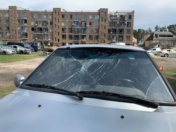 Yıkılan binaların arka planında yanmış ve bomboş bir araba. Evin kalıntıları ve arabanın gövdesinde kurşun izleri var. Rusya ve Ukrayna arasındaki savaş, Irpin-Bucha, 10 Nisan 2022