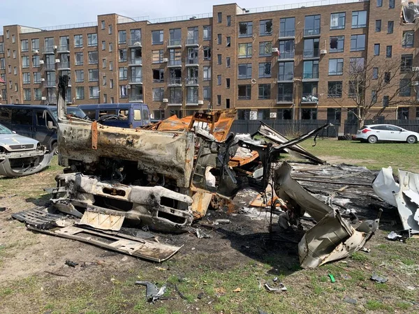 Yıkılan binaların arka planında yanmış ve bomboş bir araba. Evin kalıntıları ve arabanın gövdesinde kurşun izleri var. Rusya ve Ukrayna arasındaki savaş, Irpin-Bucha, 10 Nisan 2022