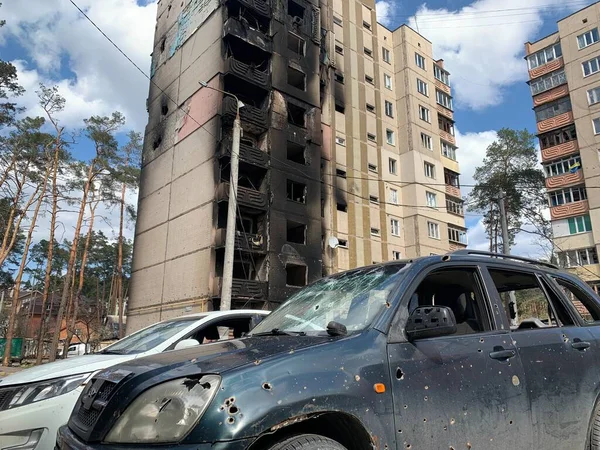 Yıkılan binaların arka planında yanmış ve bomboş bir araba. Evin kalıntıları ve arabanın gövdesinde kurşun izleri var. Rusya ve Ukrayna arasındaki savaş, Irpin-Bucha, 10 Nisan 2022
