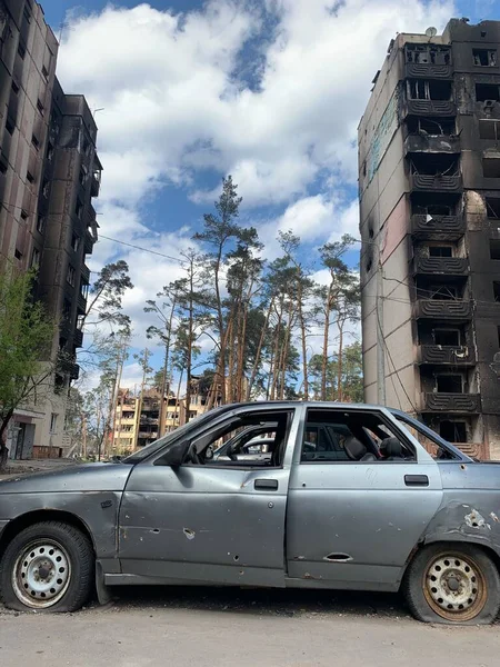 Yıkılan binaların arka planında yanmış ve bomboş bir araba. Evin kalıntıları ve arabanın gövdesinde kurşun izleri var. Rusya ve Ukrayna arasındaki savaş, Irpin-Bucha, 10 Nisan 2022