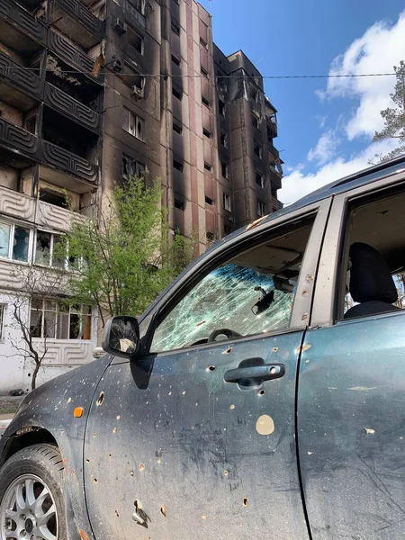 Yıkılan binaların arka planında yanmış ve bomboş bir araba. Evin kalıntıları ve arabanın gövdesinde kurşun izleri var. Rusya ve Ukrayna arasındaki savaş, Irpin-Bucha, 10 Nisan 2022
