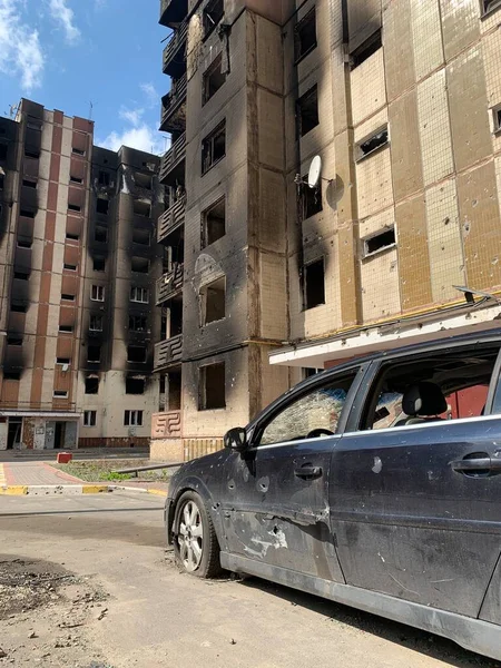 Yıkılan binaların arka planında yanmış ve bomboş bir araba. Evin kalıntıları ve arabanın gövdesinde kurşun izleri var. Rusya ve Ukrayna arasındaki savaş, Irpin-Bucha, 10 Nisan 2022
