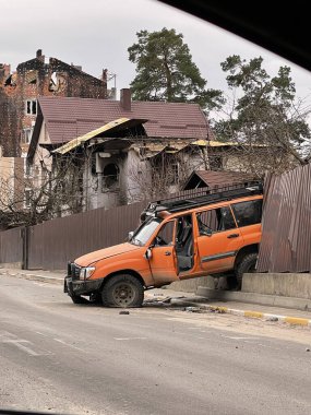 Yolun kenarında patlamış bir araba var. Çitlere ateş edilmiş. Rusya 'nın Ukrayna' daki savaşı, Irpin - Bucha, 5 Nisan 2022