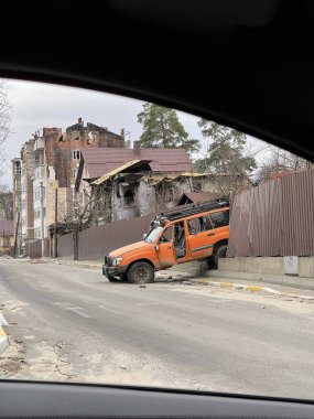 Yolun kenarında patlamış bir araba var. Çitlere ateş edilmiş. Rusya 'nın Ukrayna' daki savaşı, Irpin - Bucha, 5 Nisan 2022
