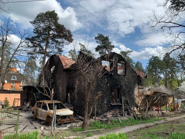 Yanmış bir araba ve yıkılmış bir bina. Bombardımandan zarar gören bir evin kalıntıları. Rusya ve Ukrayna arasındaki savaş, Irpin - Bucha, 10 Nisan 2022