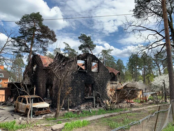 Yanmış bir araba ve yıkılmış bir bina. Bombardımandan zarar gören bir evin kalıntıları. Rusya ve Ukrayna arasındaki savaş, Irpin - Bucha, 10 Nisan 2022