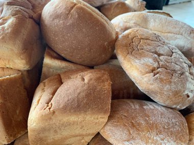 Masada bir sürü somun ekmek var. Ekmek bir bütün ve ikiye bölünmüş. Kavram: insanlara yardım etmek için buğday pişirme.