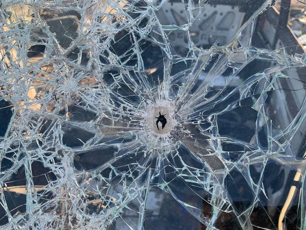 Car windshield with a bullet hole. The car was damaged after the shelling. Traces of shots on the body of the car. War between Russia and Ukraine
