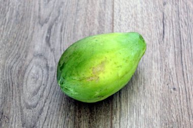 Unripe papaya fruit isolated on wood background