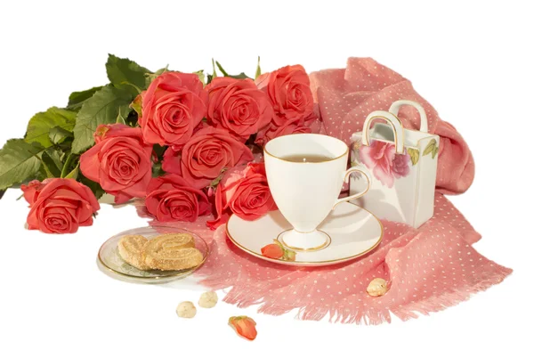 La taza blanca, rosas anaranjadas, una bufanda rosa, galletas, nueces, rodajas de azúcar se aíslan sobre un fondo blanco . —  Fotos de Stock