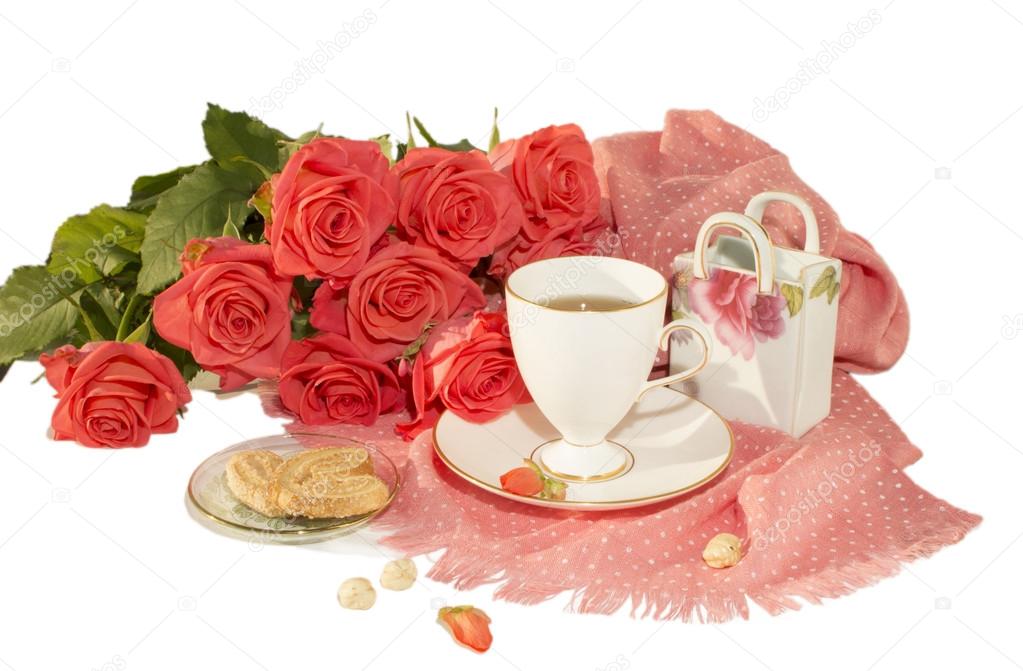 The white cup, orange roses, a pink scarf, cookies, nuts, slices of sugar are isolated on a white background.