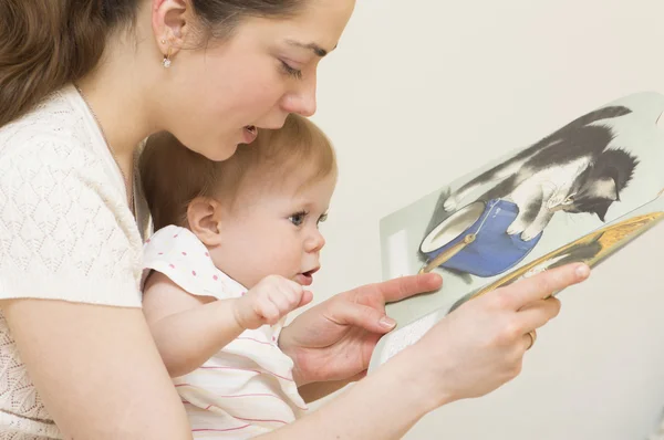 De moeder leest het boek aan de baby. — Stockfoto