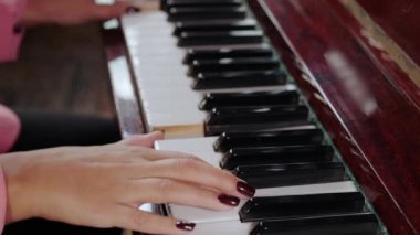 Piyano çalan genç bir kız. Siyah-beyaz tuşlar üzerinde kızın güzel parmakları. Eller yukarı.