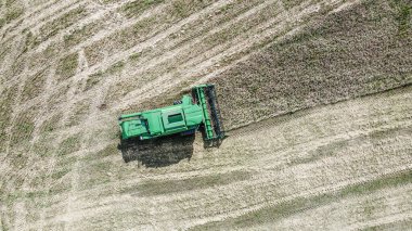 Güneşli bir akşamda tarlada çalışan hasat makinesinin hava görüntüsü. Sanayi tarımı.