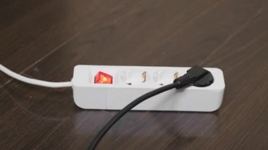 Kadının eli elektriği kesiyor. Güç şeridi yerde..