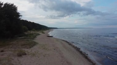 Plaj ve deniz manzaralı, yağmur bulutlu. Yuvarlanan dalgalarla kıyı şeridi perspektifi.