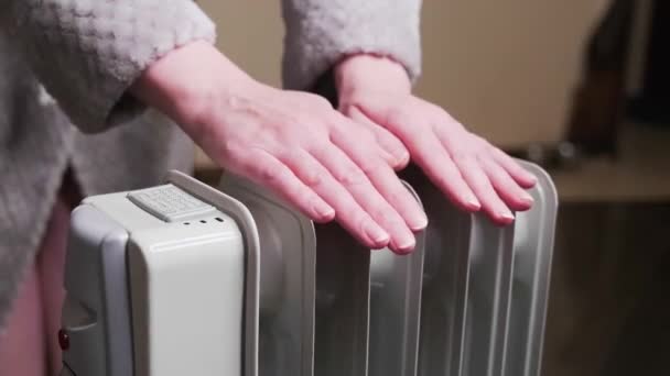 Жінка Нагріває Руки Рухомому Масляному Обігрівачі Вдома Холодно — стокове відео