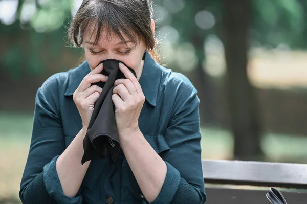 A woman covers her nose with a handkerchief, spring and summer allergies during flowering.